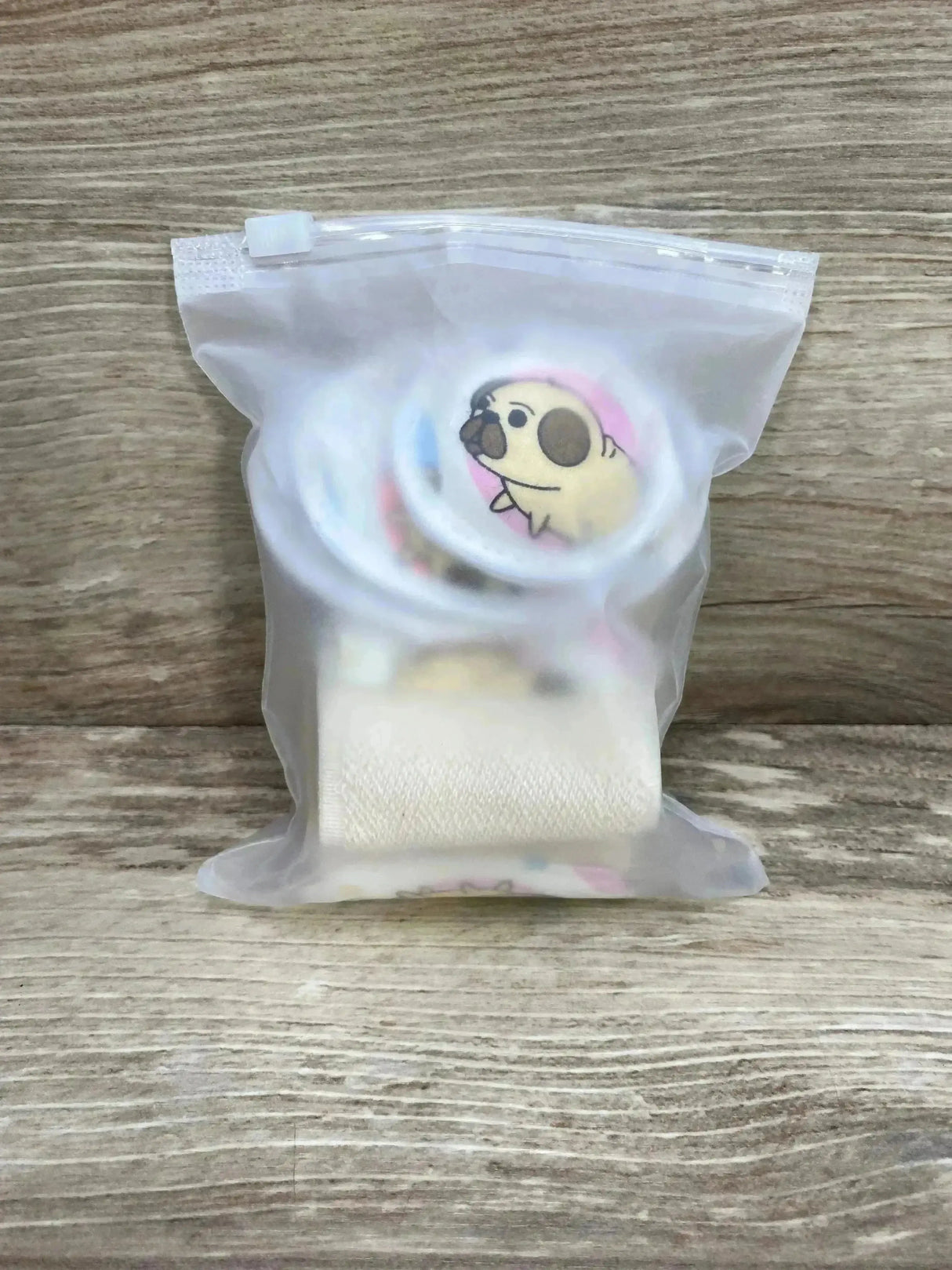 Front view of Bojje umbilical hernia belt and round adhesive belly pads in a translucent resealable bag on wood background