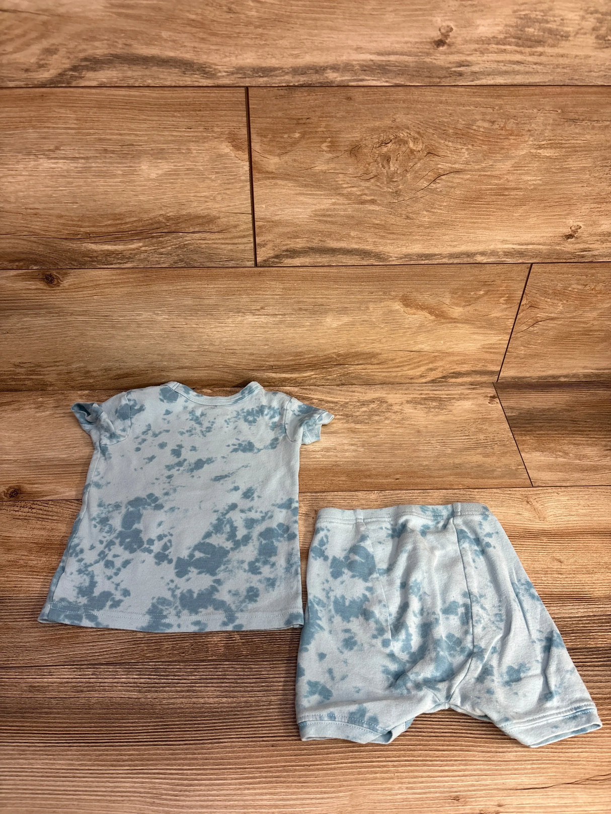 Blue and white tie-dye baby outfit with short sleeve top and shorts on wooden floor