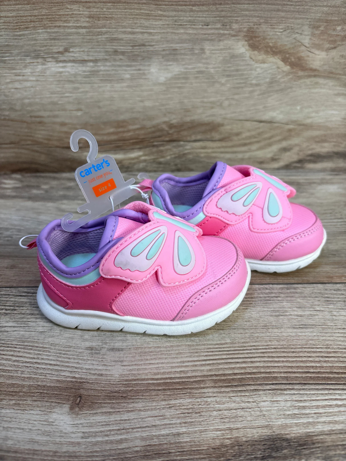 Pink baby sneakers with butterfly wing Velcro, size 4, on wood background