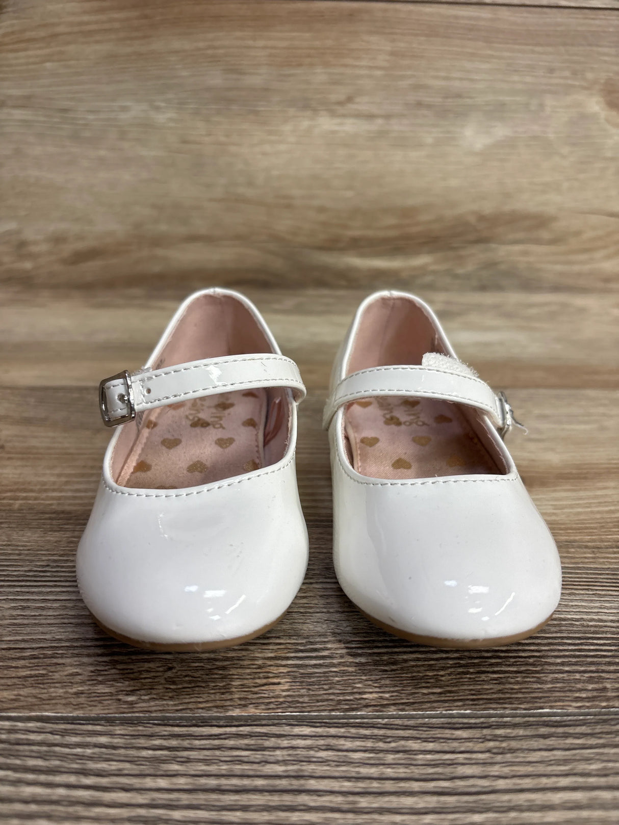 Pair of white toddler Mary Jane shoes with buckles on wooden background