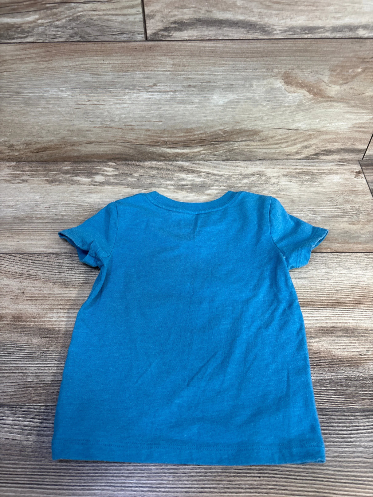 Back view of Cat & Jack blue toddler t-shirt showcasing plain back and short sleeves on wooden surface