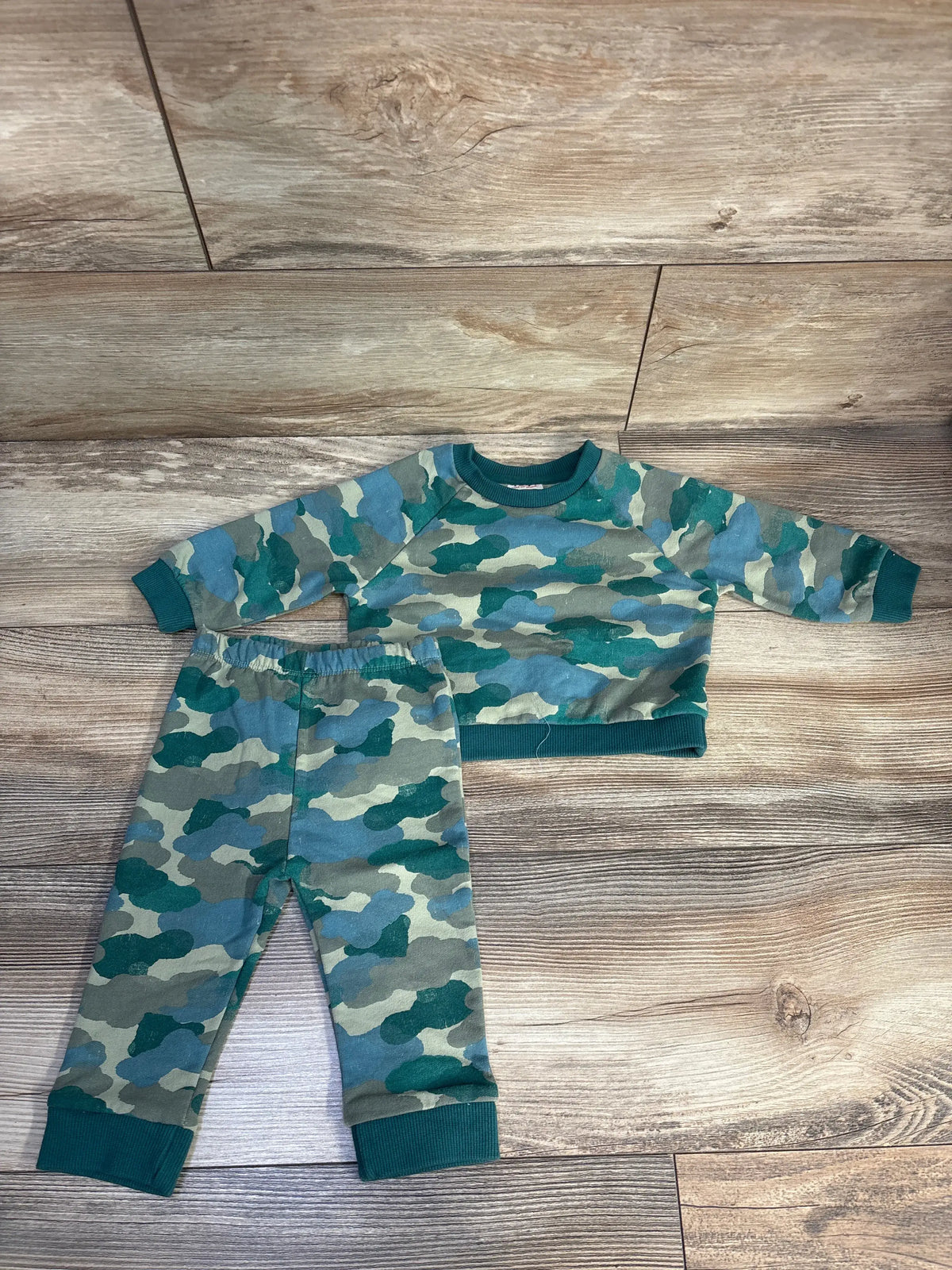 Flat lay of Cat and Jack green camo sweatshirt and joggers set, size 6 to 9 months, with ribbed cuffs and elastic waistband