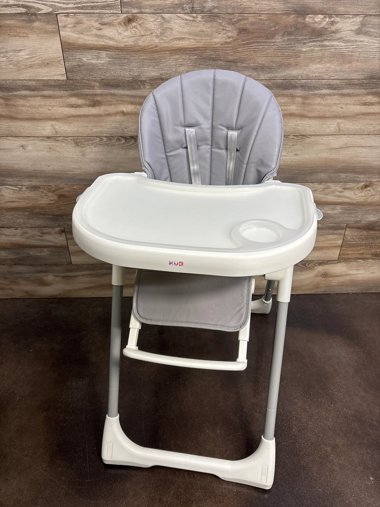 Front view of KÜB 3-in-1 foldable baby high chair showcasing grey padded seat, safety harness, and removable white tray with cup holder