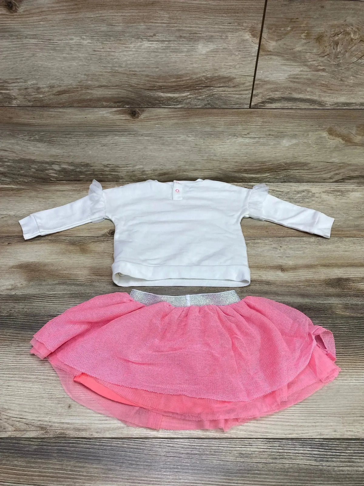 Back view of Cat and Jack 2pc set showcasing white sweatshirt and pink tulle tutu skirt flat lay on wood plank floor