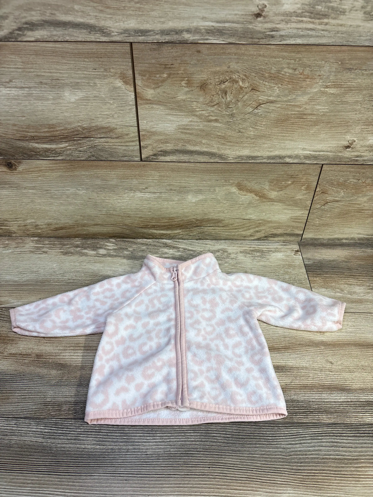Front view of pink leopard fleece jacket for 0 to 3 months, showing zip front and stand collar on wood floor
