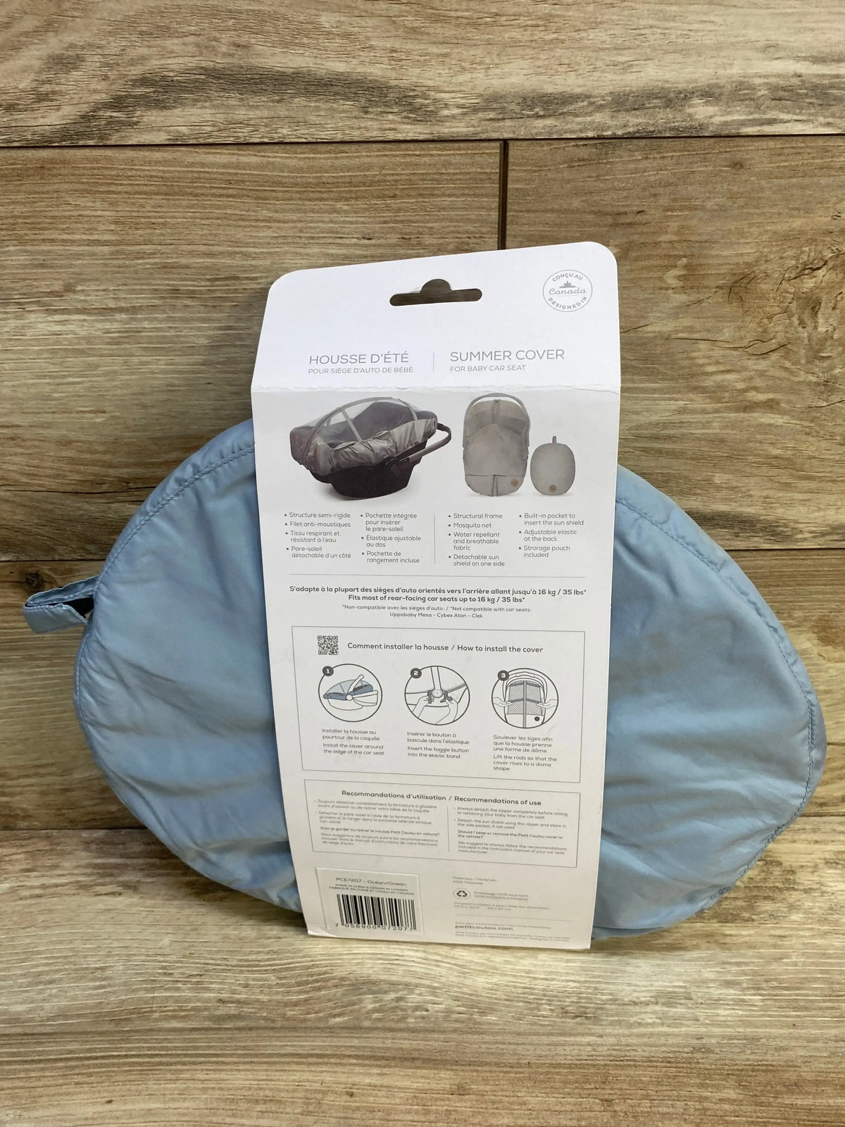 Front of folded blue summer car seat cover in packaging with diagrams and SUMMER COVER text on wood background