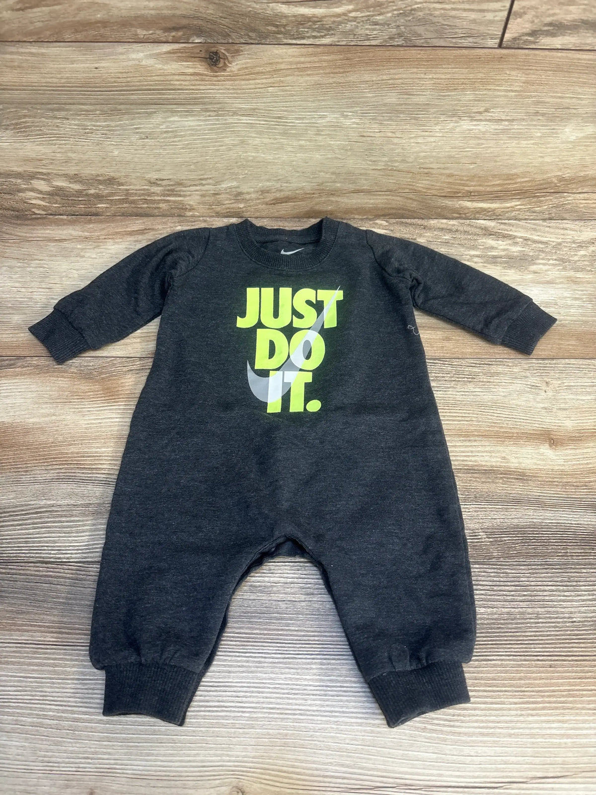 Dark gray baby romper with long sleeves and neon yellow 'Just Do It.' text on wood floor