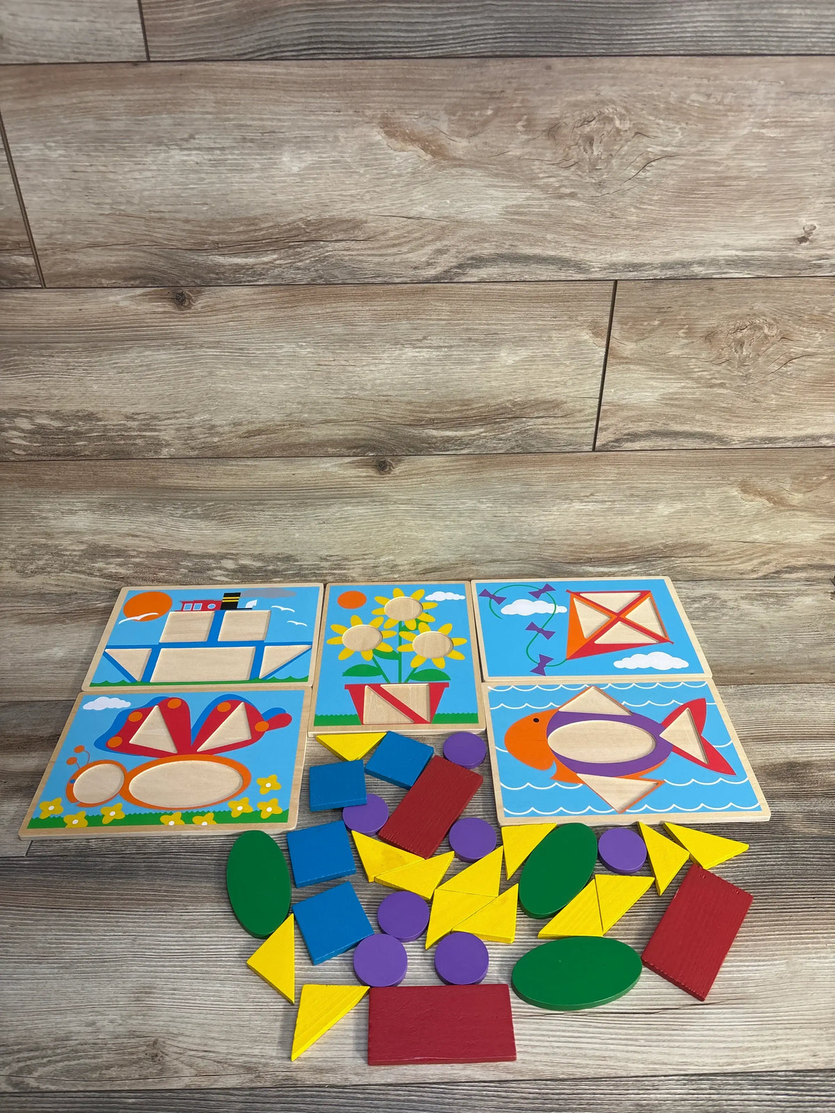 Overhead view of Best Learning Learning Cube showcasing colorful wooden puzzle boards and loose geometric pieces on a wood floor
