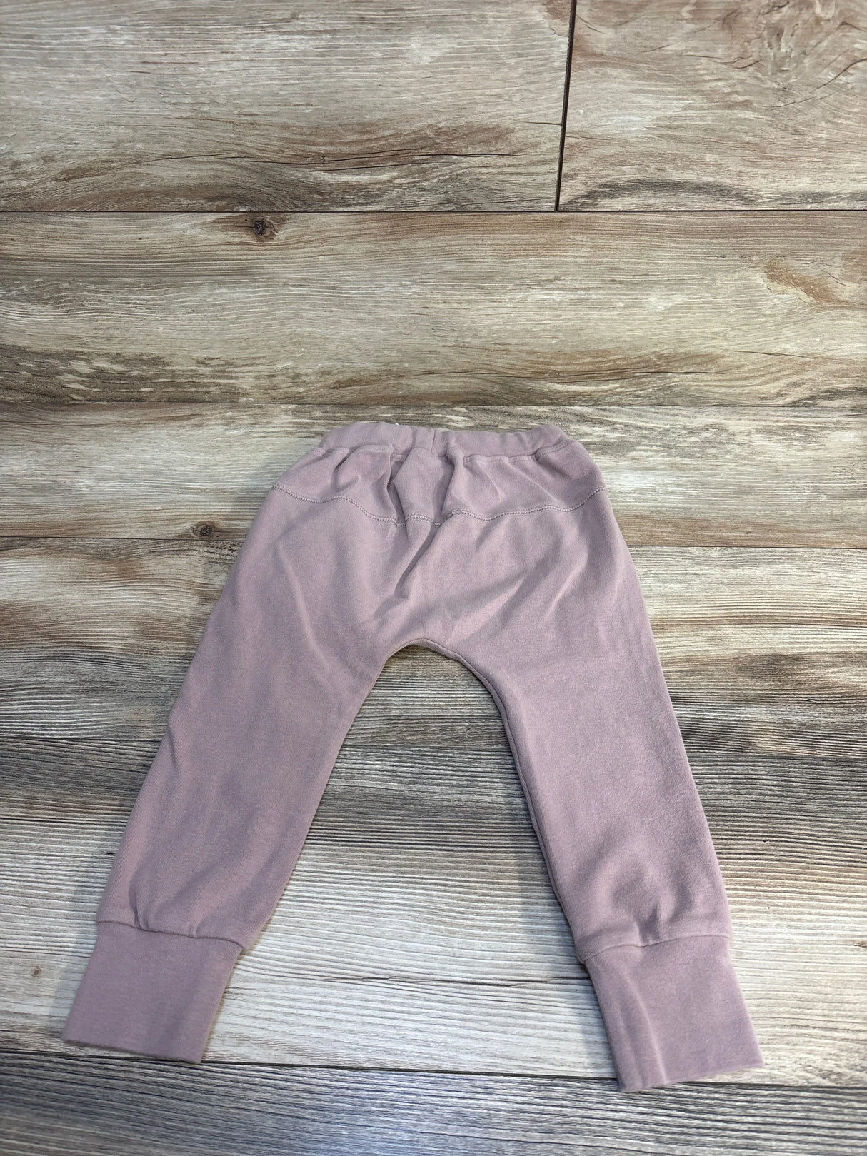 Light mauve toddler pants with elastic waistband and cuffs on wood background