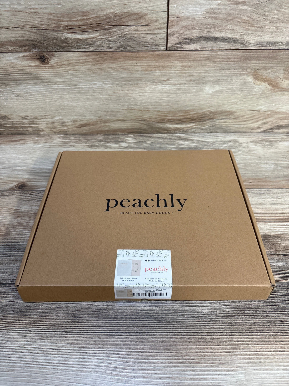 Peachly baby memory book in olive, beautiful baby goods packaging on wood floor