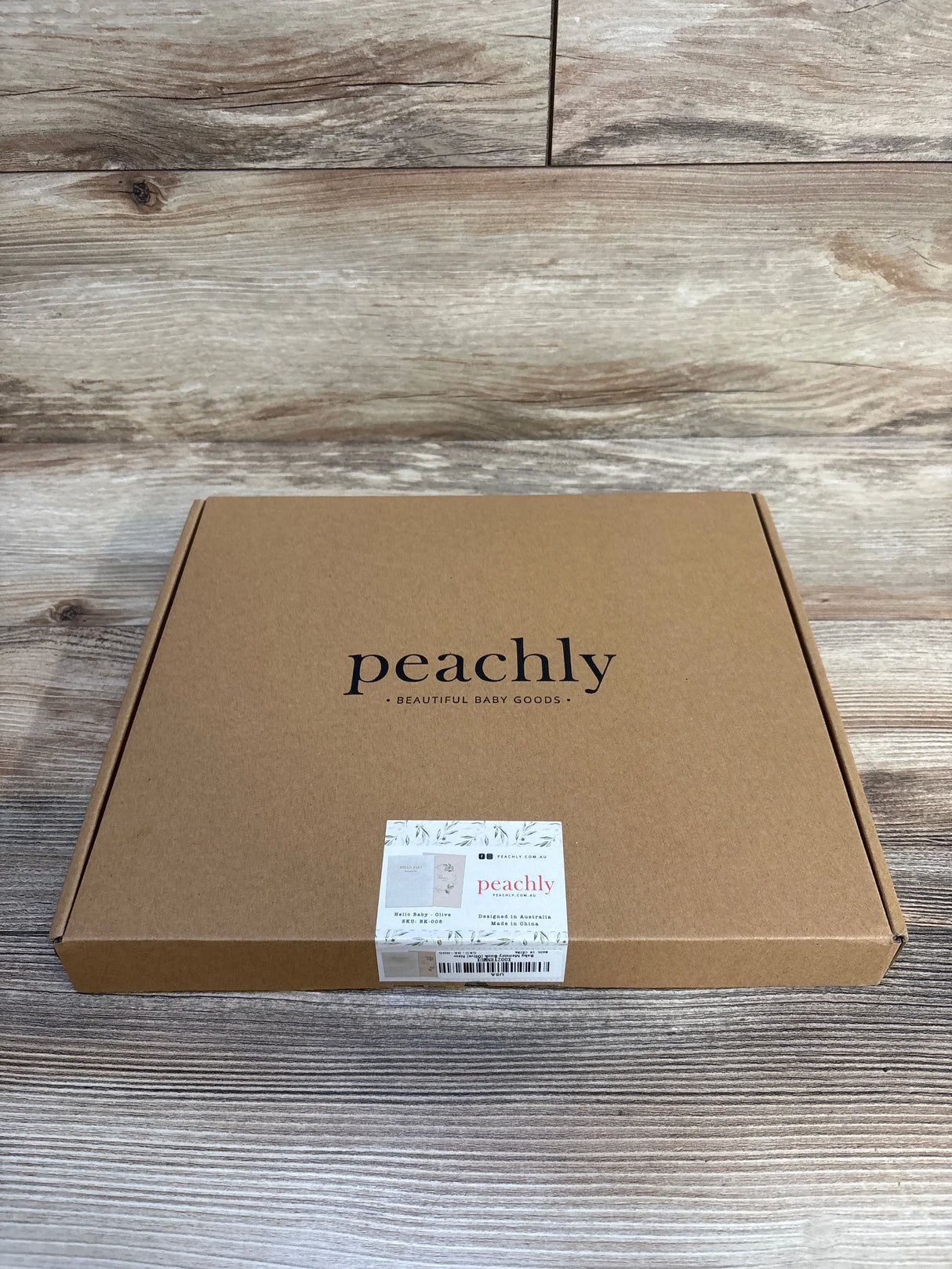 Peachly baby memory book in olive, beautiful baby goods packaging on wood floor
