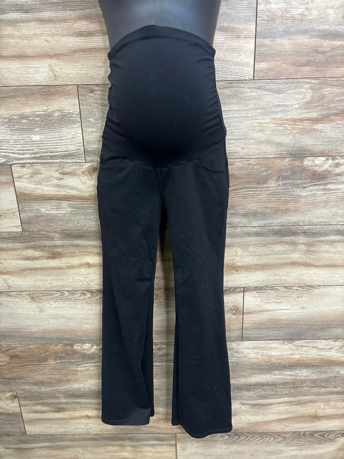 Front view of black Ewedoos maternity over-belly pants showing stretch belly panel and slight flare against wood floor