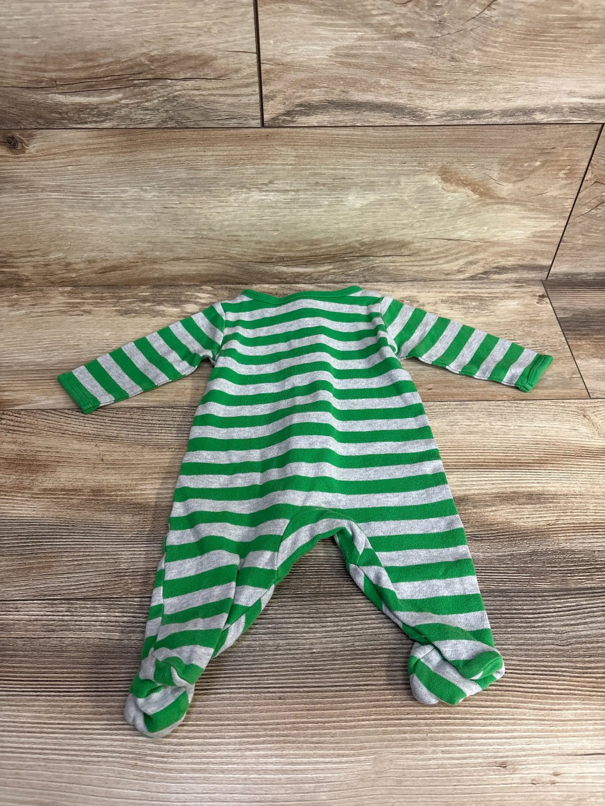 Green and gray striped baby sleeper with footies on wood background