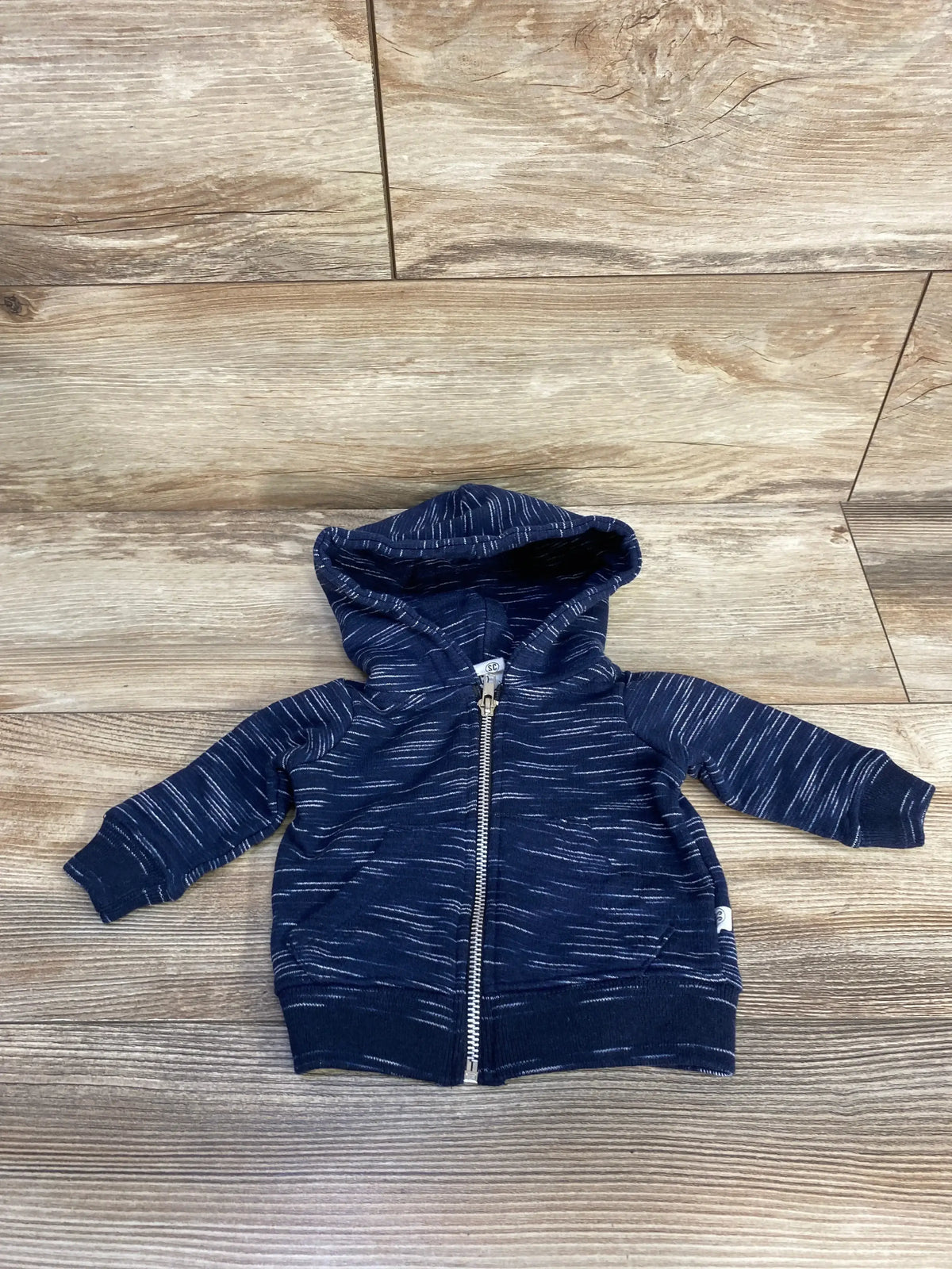 Navy blue baby hoodie with white streaks and zipper, displayed on wooden floor