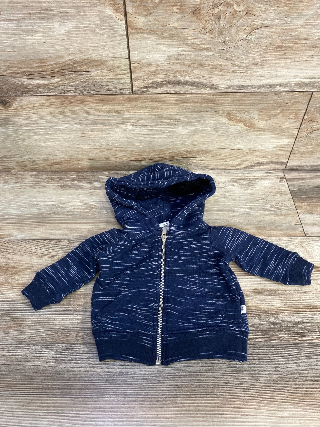Navy blue baby hoodie with white streaks and zipper, displayed on wooden floor
