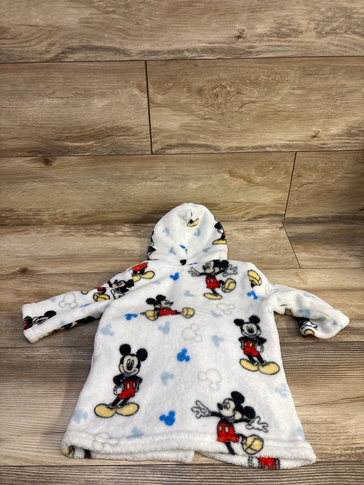 Front view of Disney Baby Mickey Mouse plush robe showcasing white plush fabric and hood on a wood floor