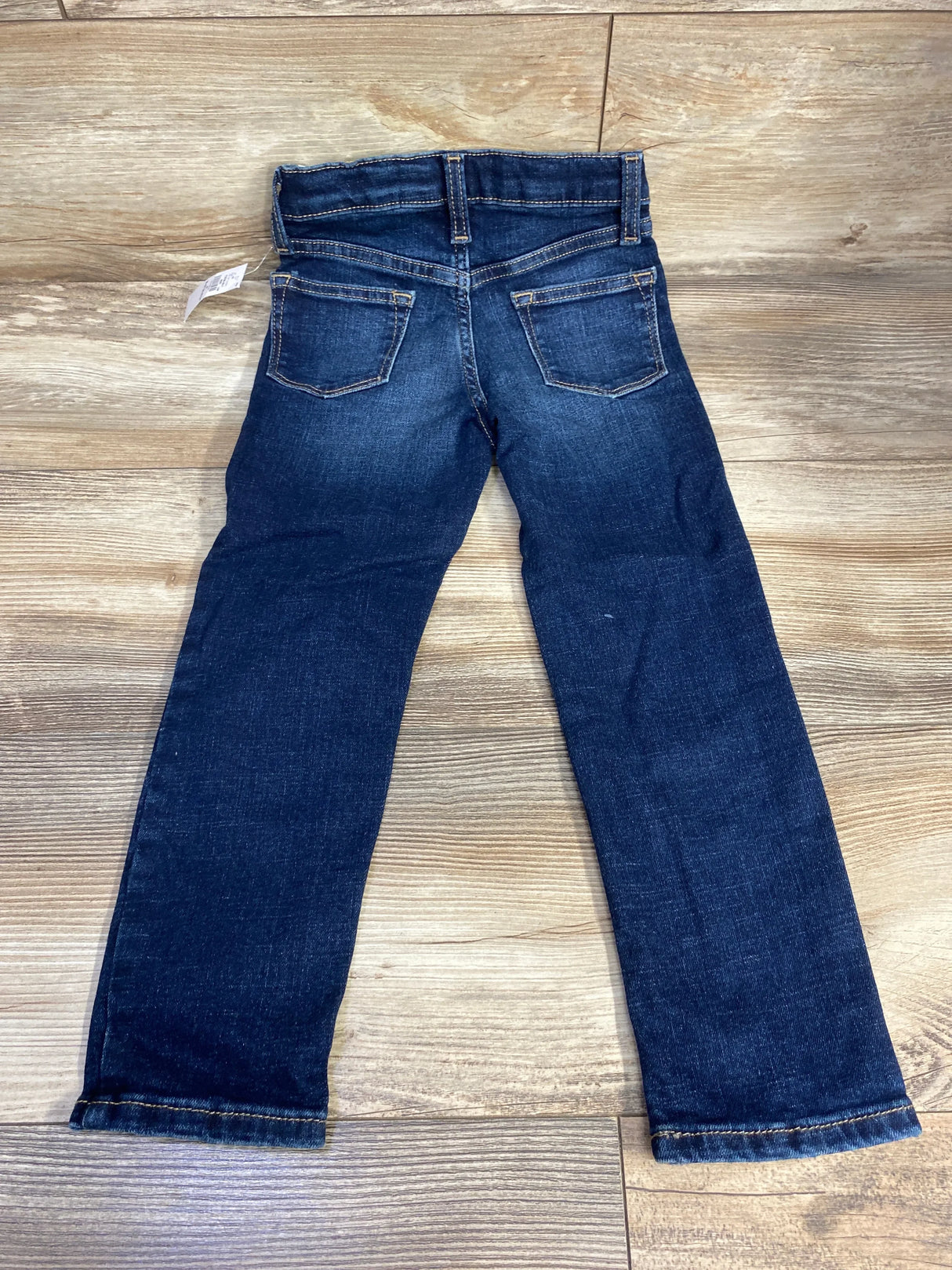 Back view of dark wash kids jeans with two pockets on wooden floor