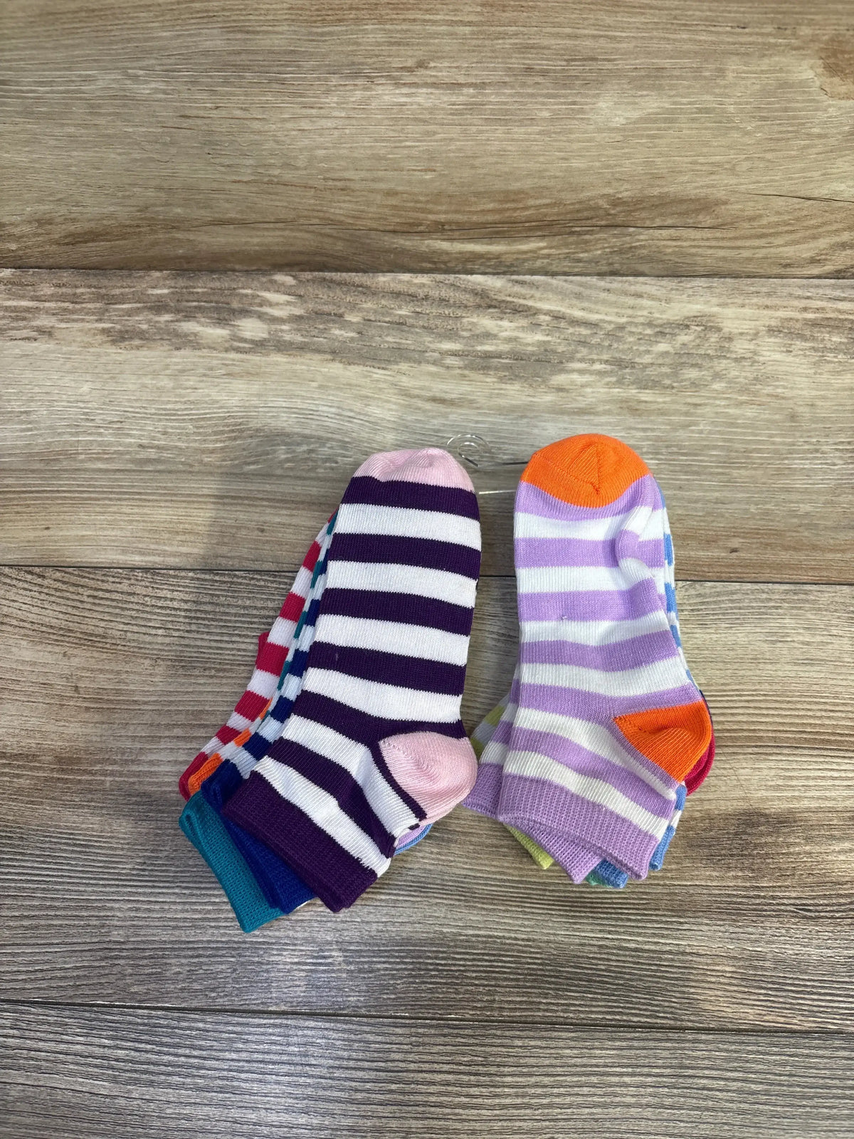 Top-down view of 9-pack children's striped ankle socks size 4-8, assorted colors on a wood floor