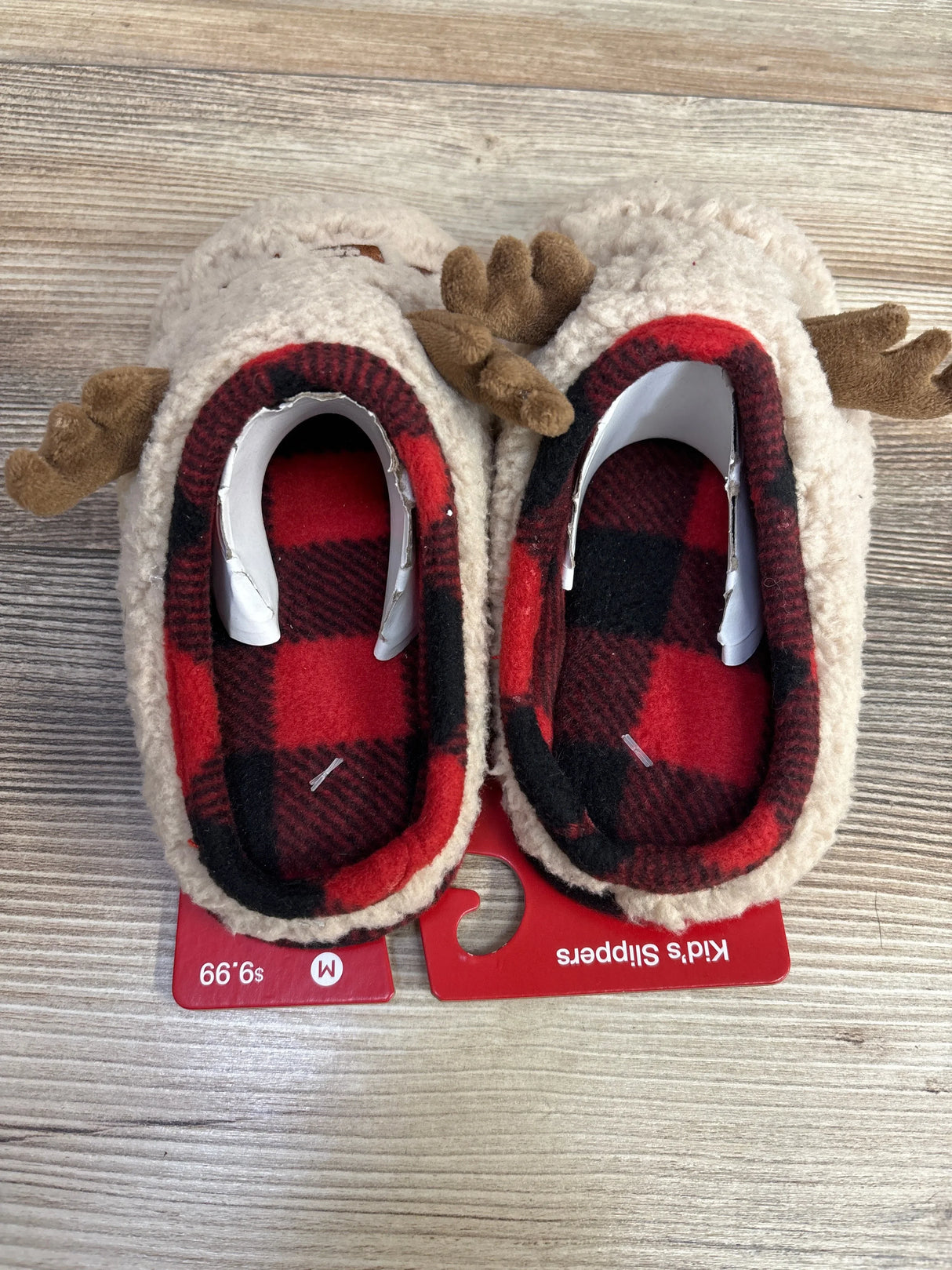 Top view of baby deer slippers size 13C-1Y showcasing plush antler details and red buffalo plaid lining on a wood surface