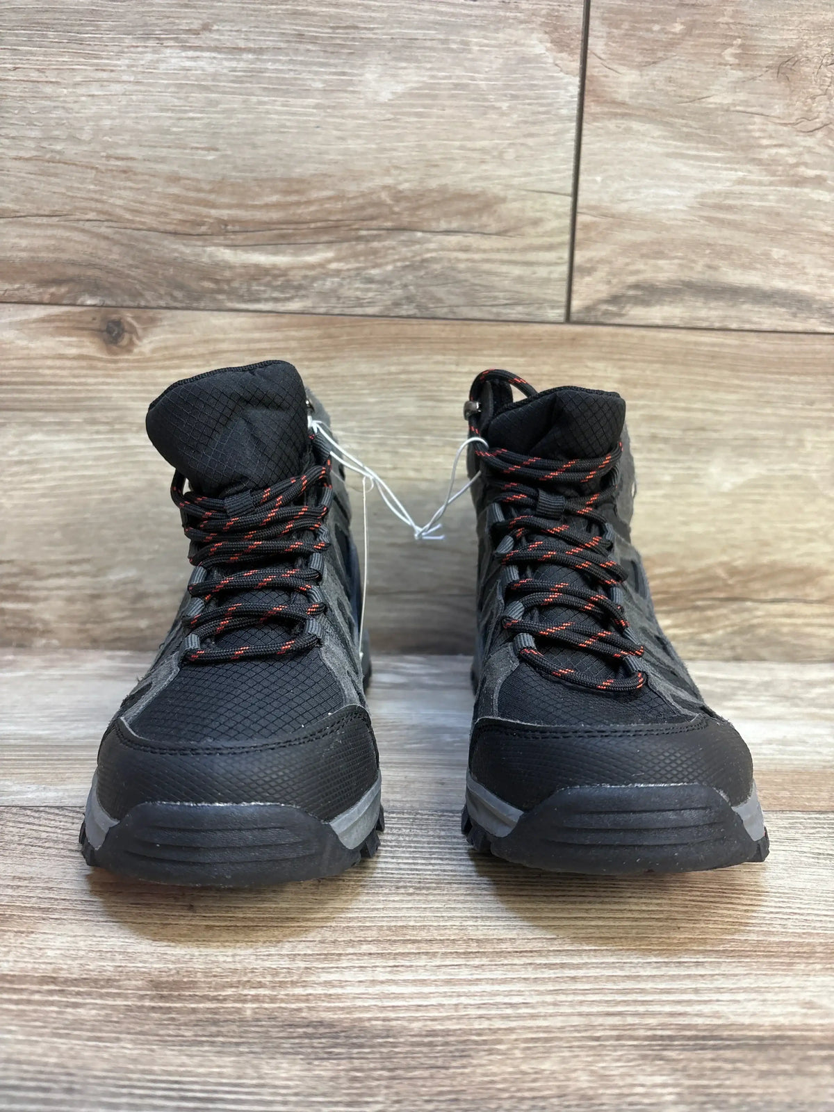 Front view of Cat and Jack Patsy kids’ hiking boots in black and gray showcasing red-accent laces and padded ankle collar on wood floor