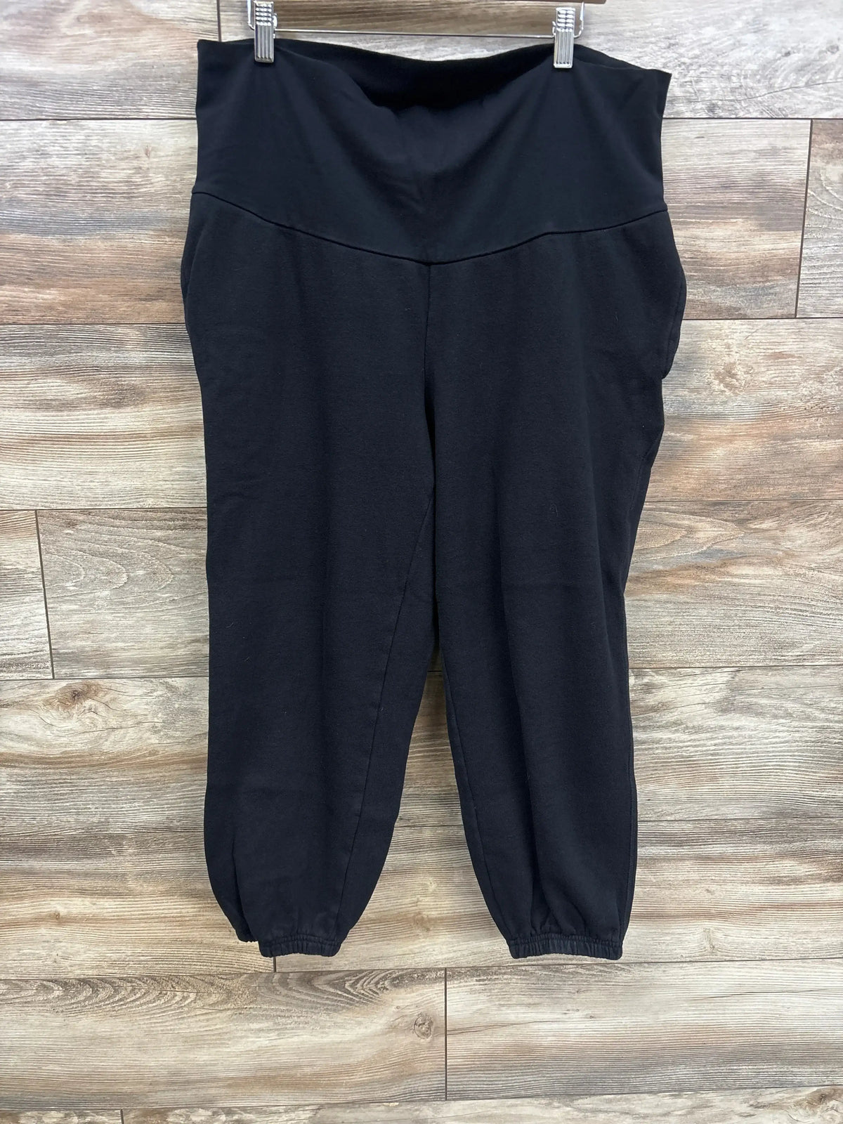 Front view of black Old Navy maternity jogger sweatpants showcasing rollover waist band and elastic ankle cuffs on wood background