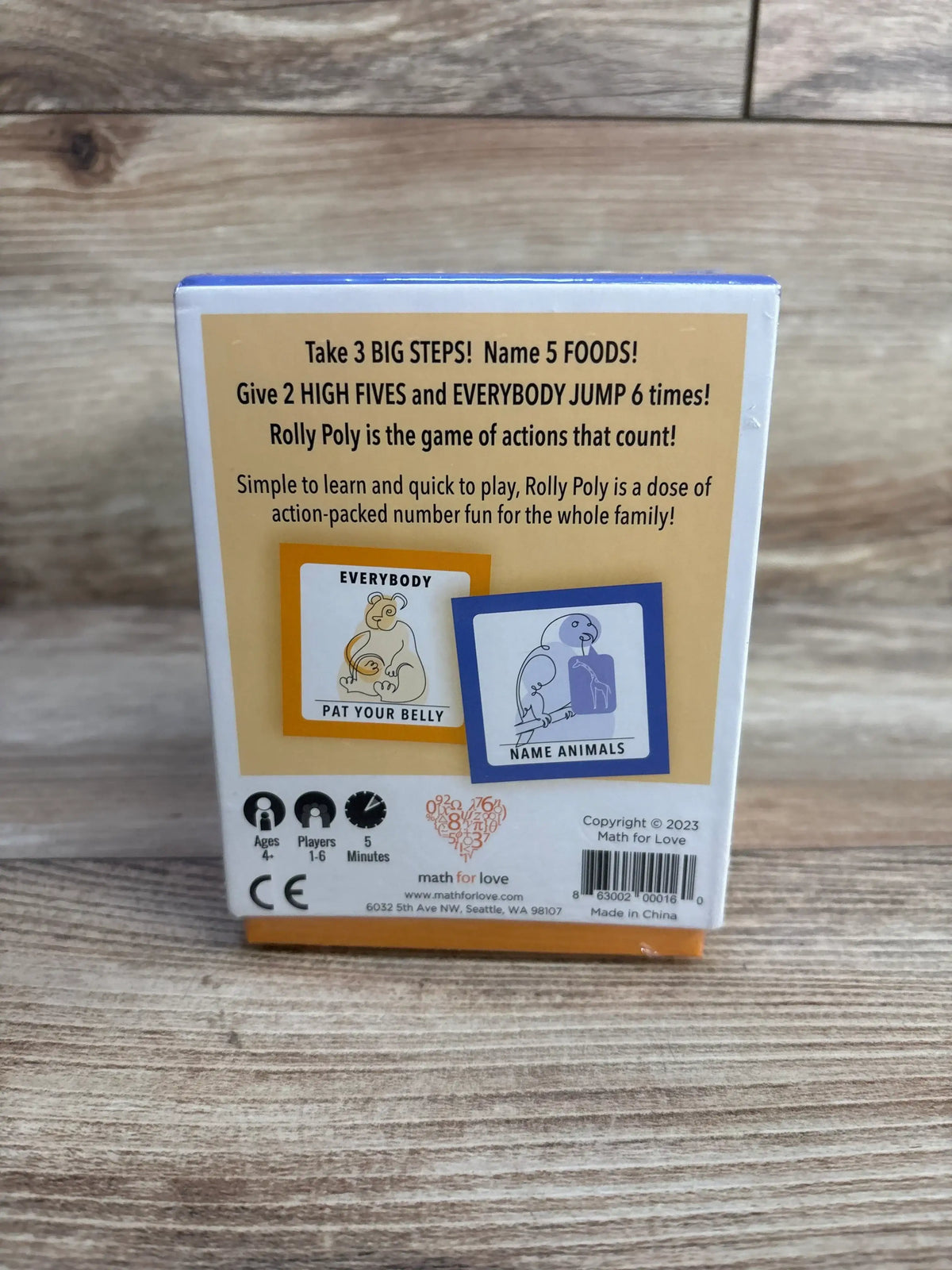 Back view of NEW Math For Love Rolly Poly number learning family game showcasing yellow box back with game description and ages 4 plus on wood plank floor