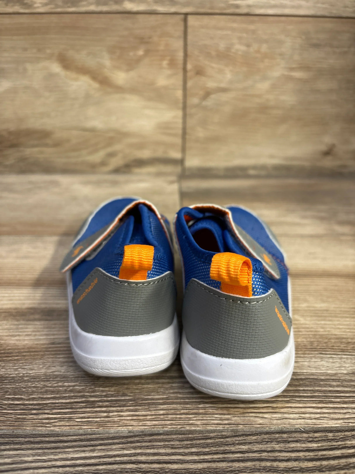 Rear view of See Kai Run Ryder FlexiRun toddler water shoes in blue with gray heel and orange pull tab on wood floor
