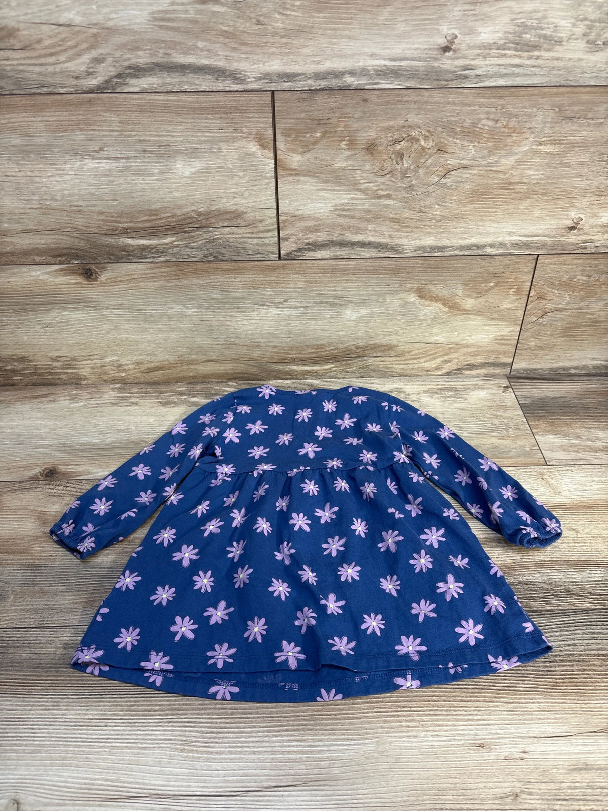 Navy blue long sleeve toddler dress with purple floral print on wood background