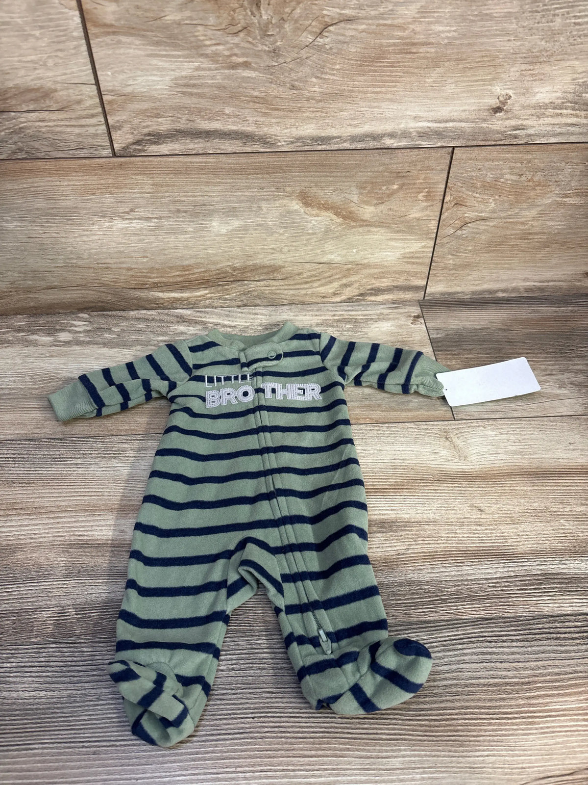 Flat lay of preemie green and navy striped footed sleeper showcasing Little Brother embroidery and front zipper on wood plank background