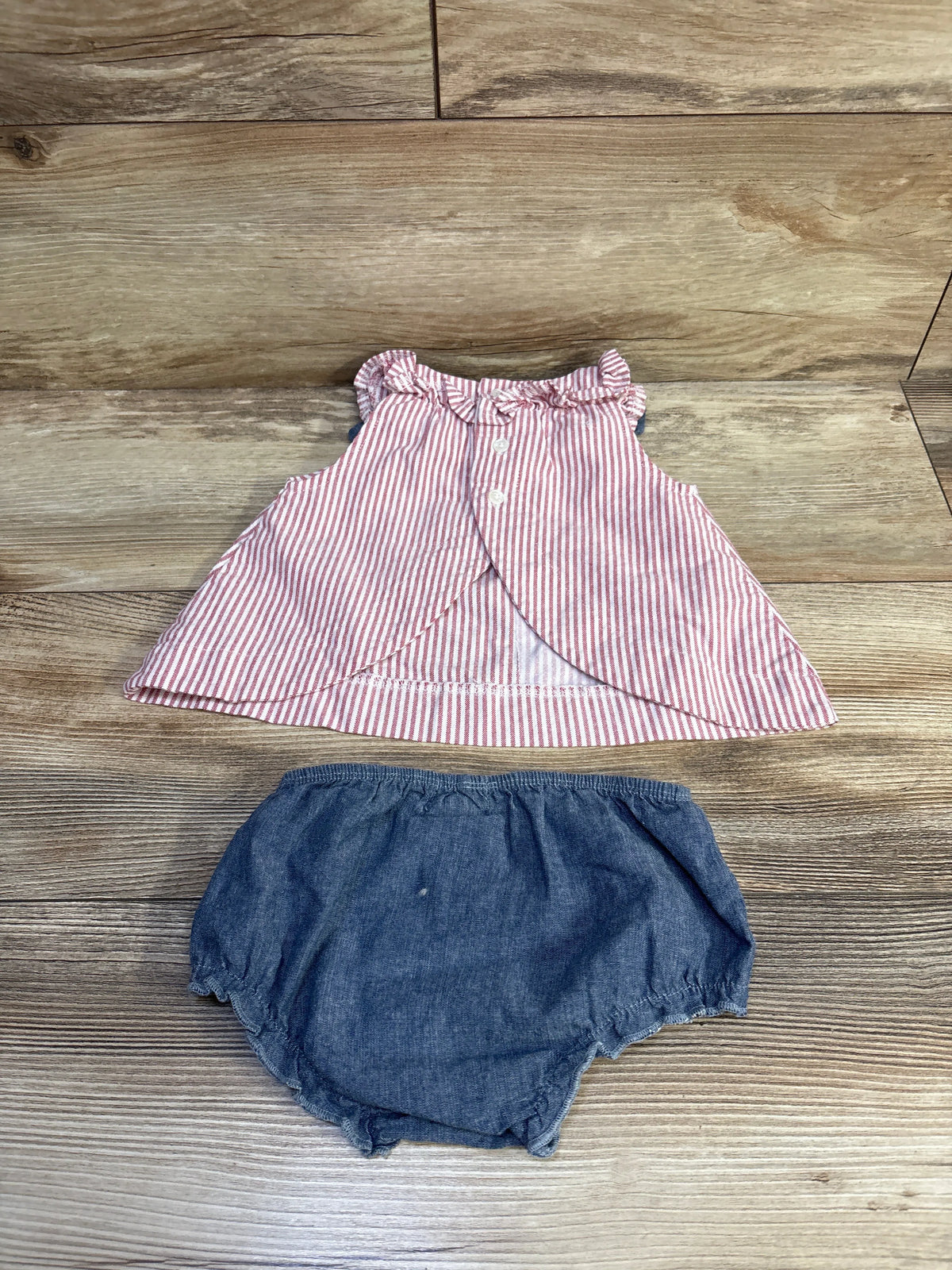 Flat lay of MudPie 2-piece red and white striped sleeveless top with ruffle collar and blue chambray bloomers on wood background