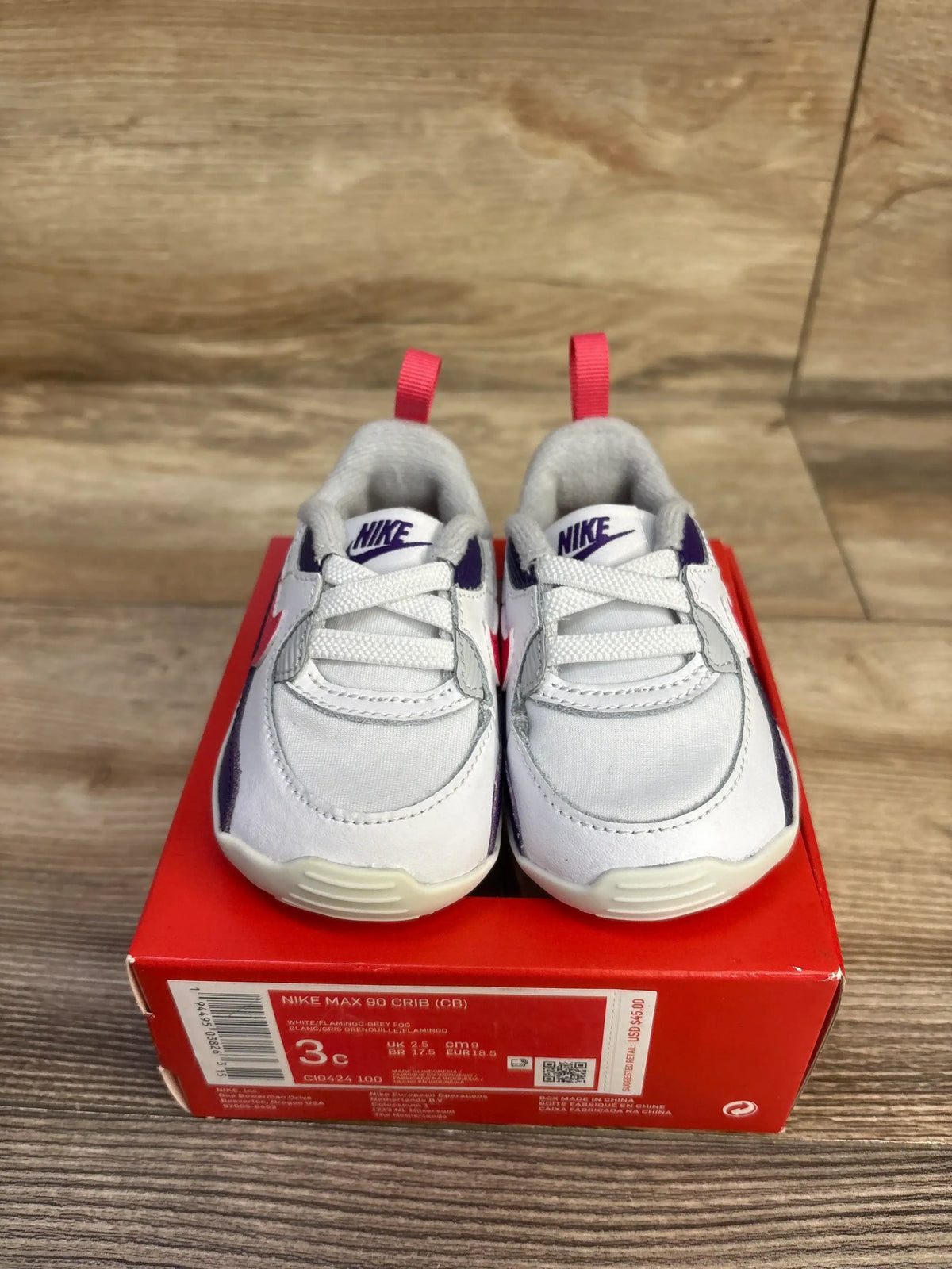 Front view of Nike Air Max 90 Crib sneakers size 3C showing white upper with purple accents and pink heel tabs on red box