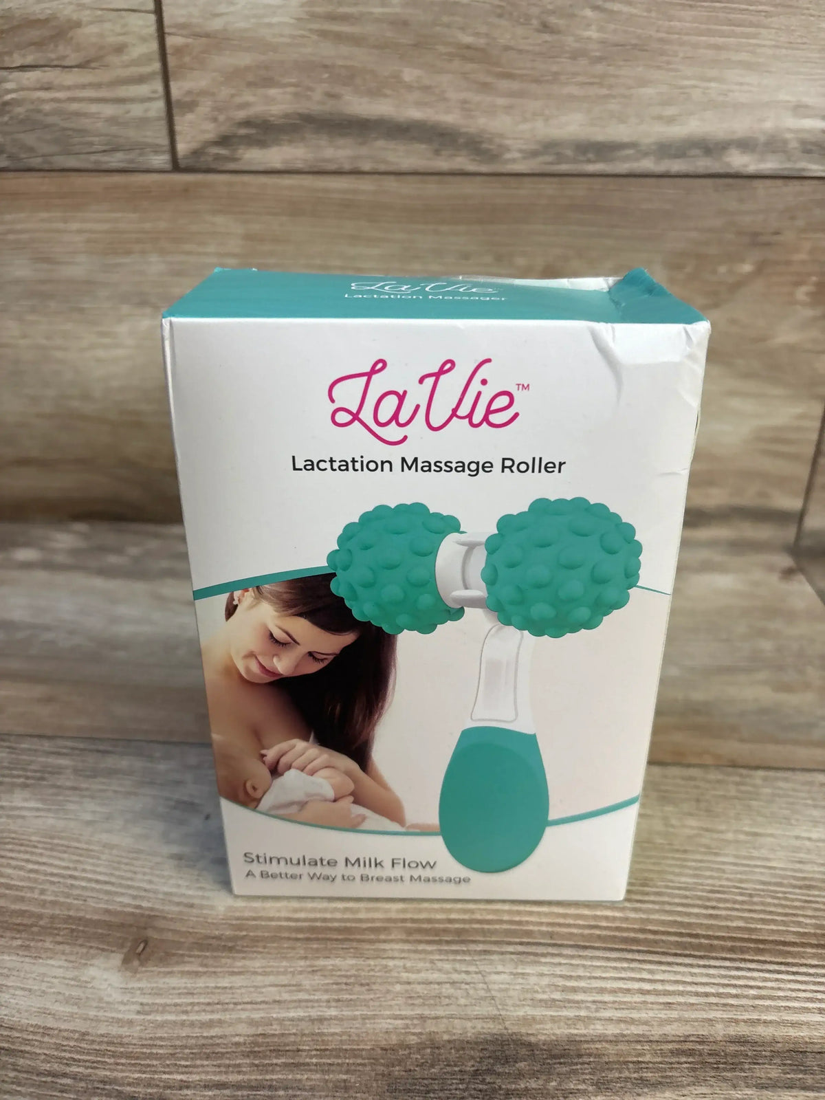 Front of LaVie Lactation Massage Roller box showing teal dual-knob roller illustration and mother breastfeeding on wood backdrop