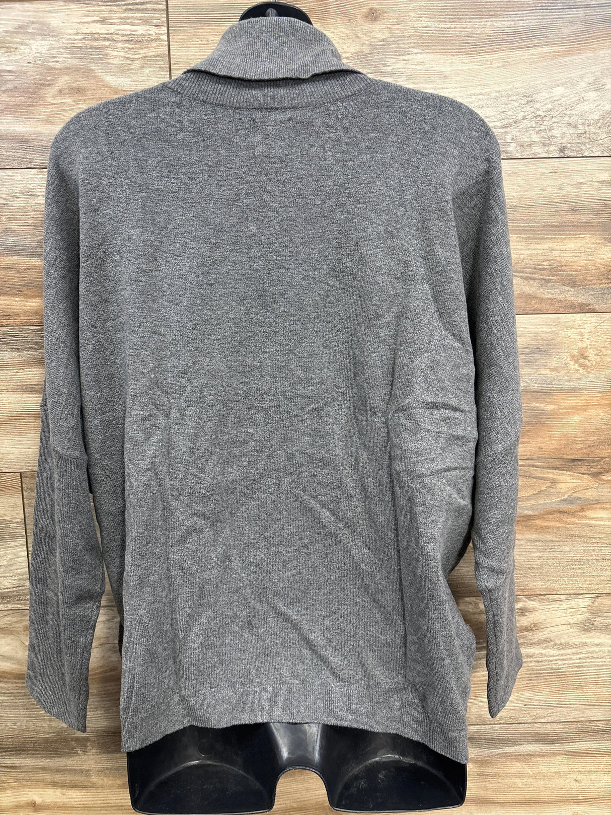 Back view of a gray long-sleeve children's sweater on a black mannequin against wooden background