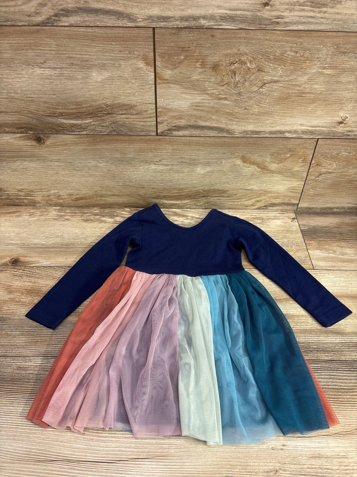 Front view of Hanna Andersson long sleeve rainbow dress with navy bodice and multicolor tulle skirt on wood background