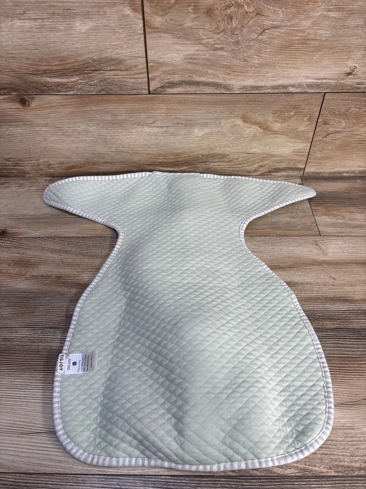Zigjoy quilted transitional swaddle in mint green, size 3-6m, on a wood-look floor