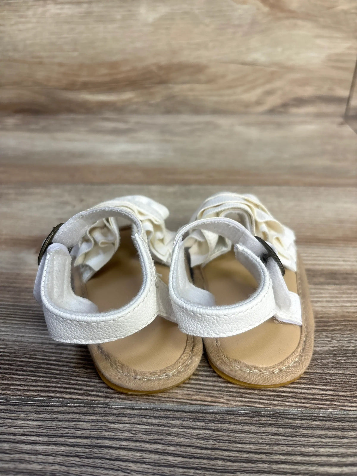 Front view of white Muchenggift bowknot soft sole sandals showcasing adjustable ankle straps on a wood-grain surface