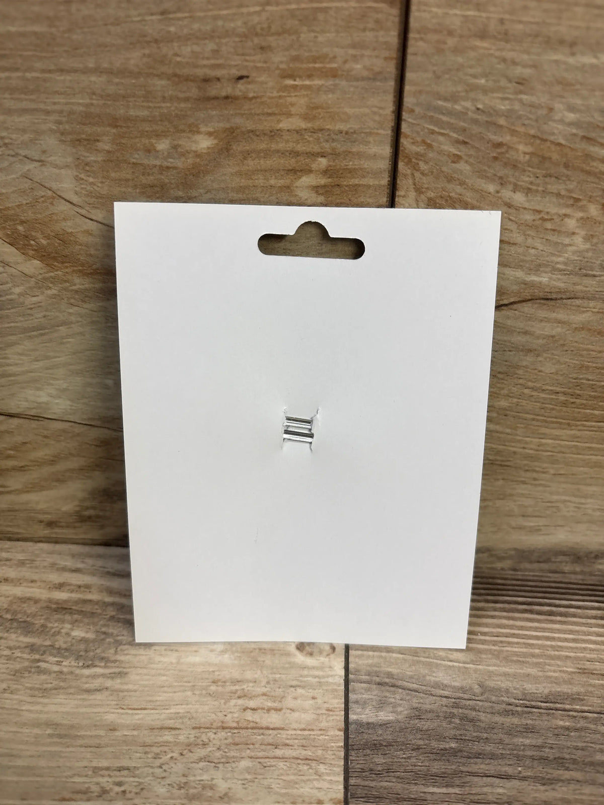 Back view of the football applique glitter hair bow showing its metal clip on a white display card over a wooden surface