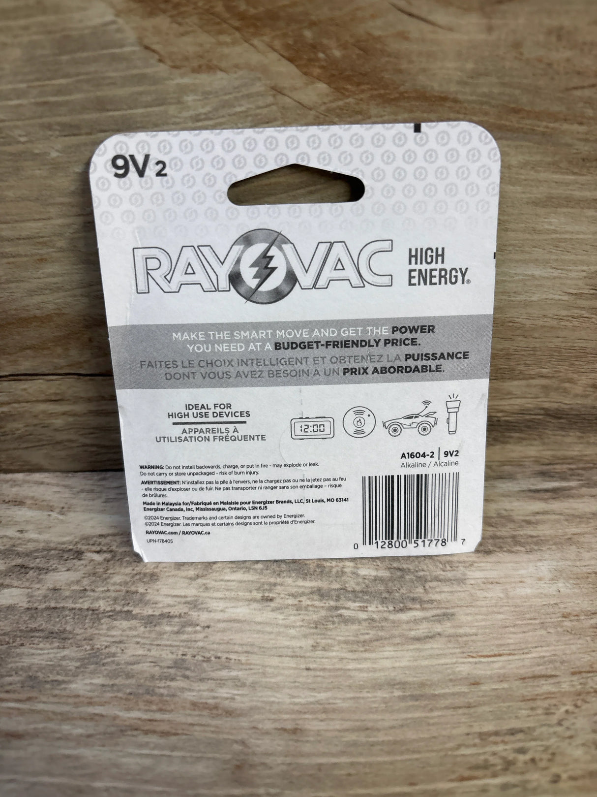 Rear view of 9V battery 2-pack showing Rayovac logo, High Energy text, barcode and warnings on wooden tabletop
