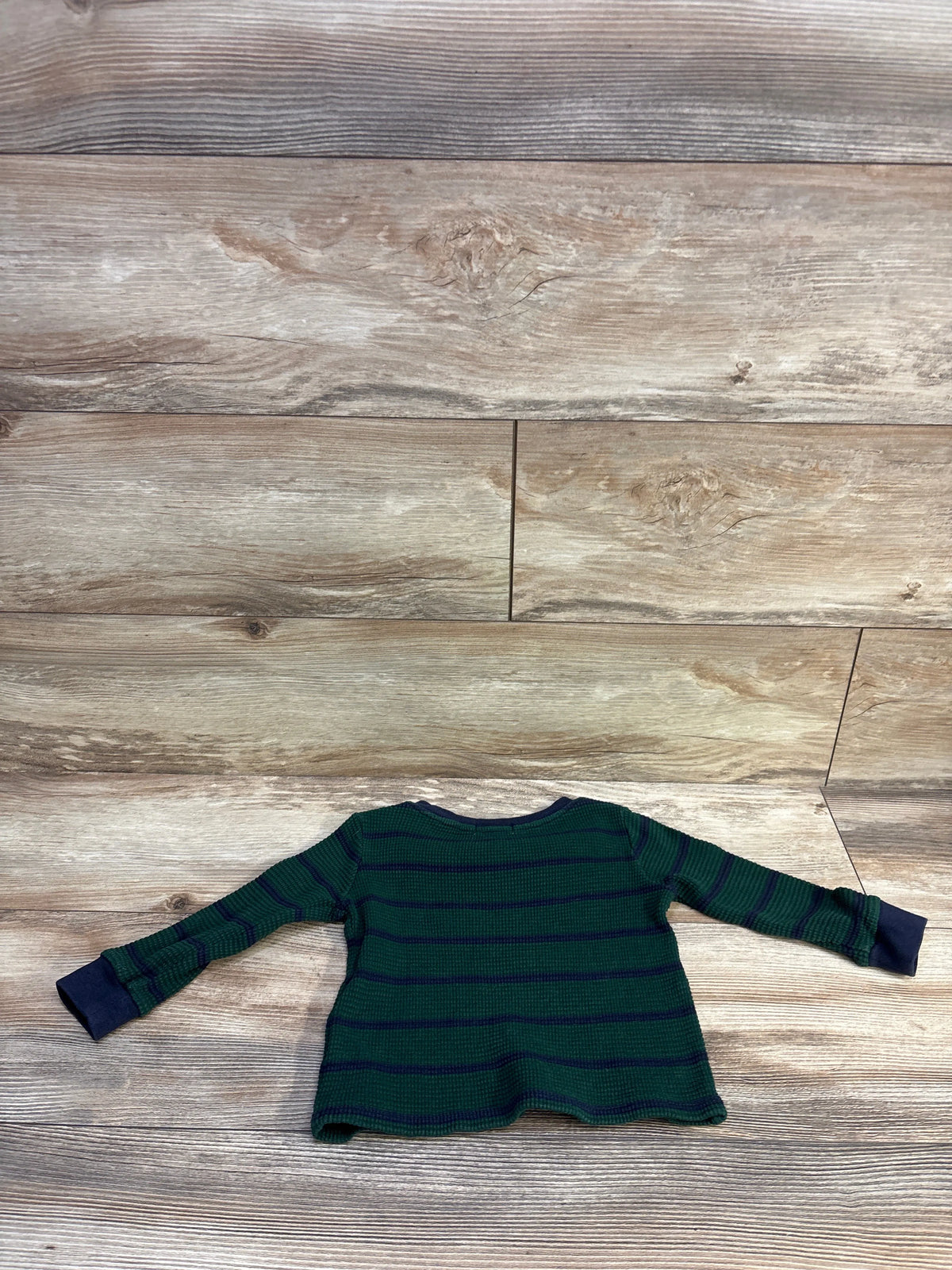 Back flat lay of Ralph Lauren waffle knit long-sleeve baby shirt showing green with navy horizontal stripes and navy cuffs on wood