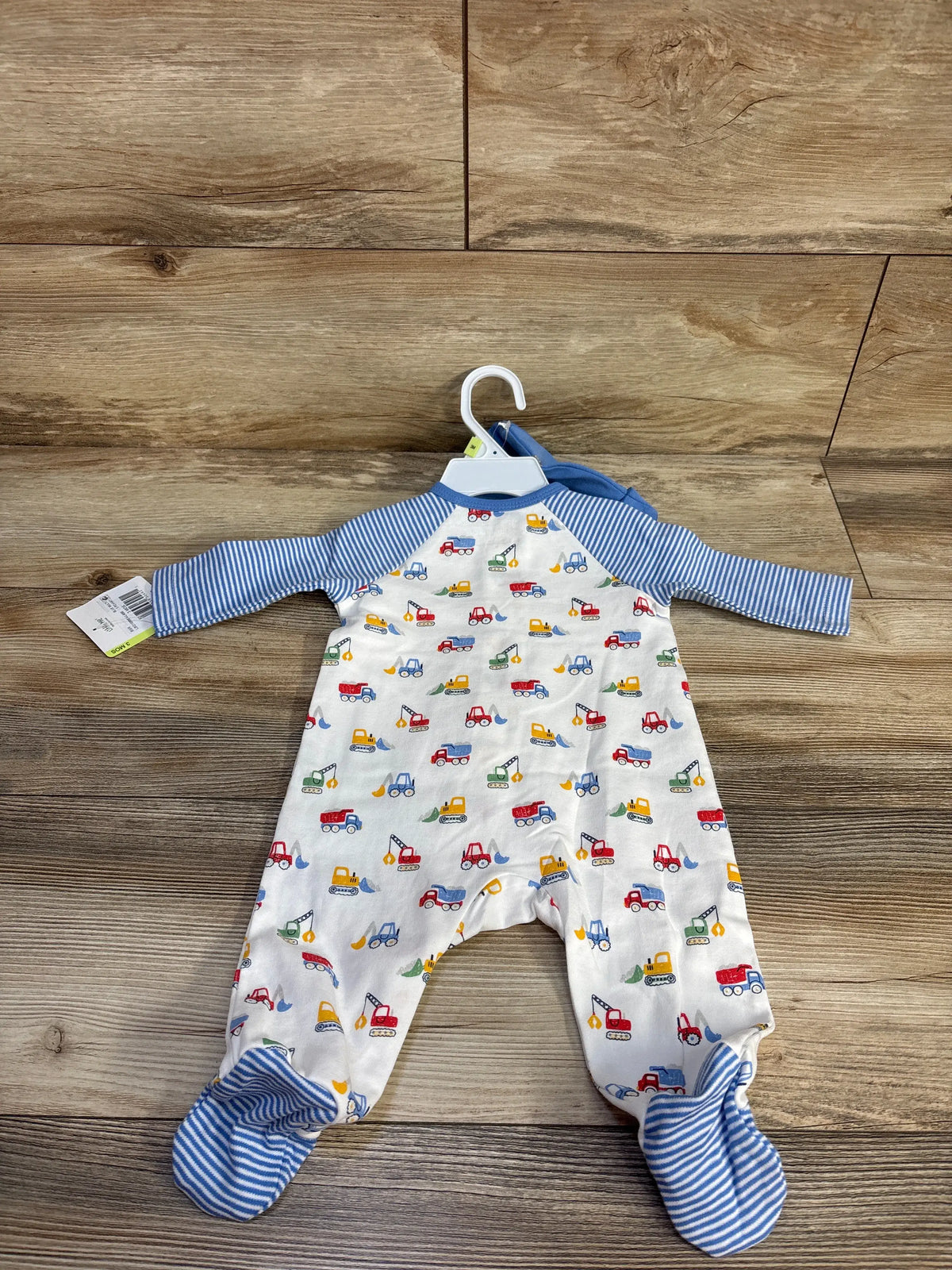 Front view of Little Me 2-piece sleeper and hat set showing white footed sleeper with blue stripes and construction vehicles on wood