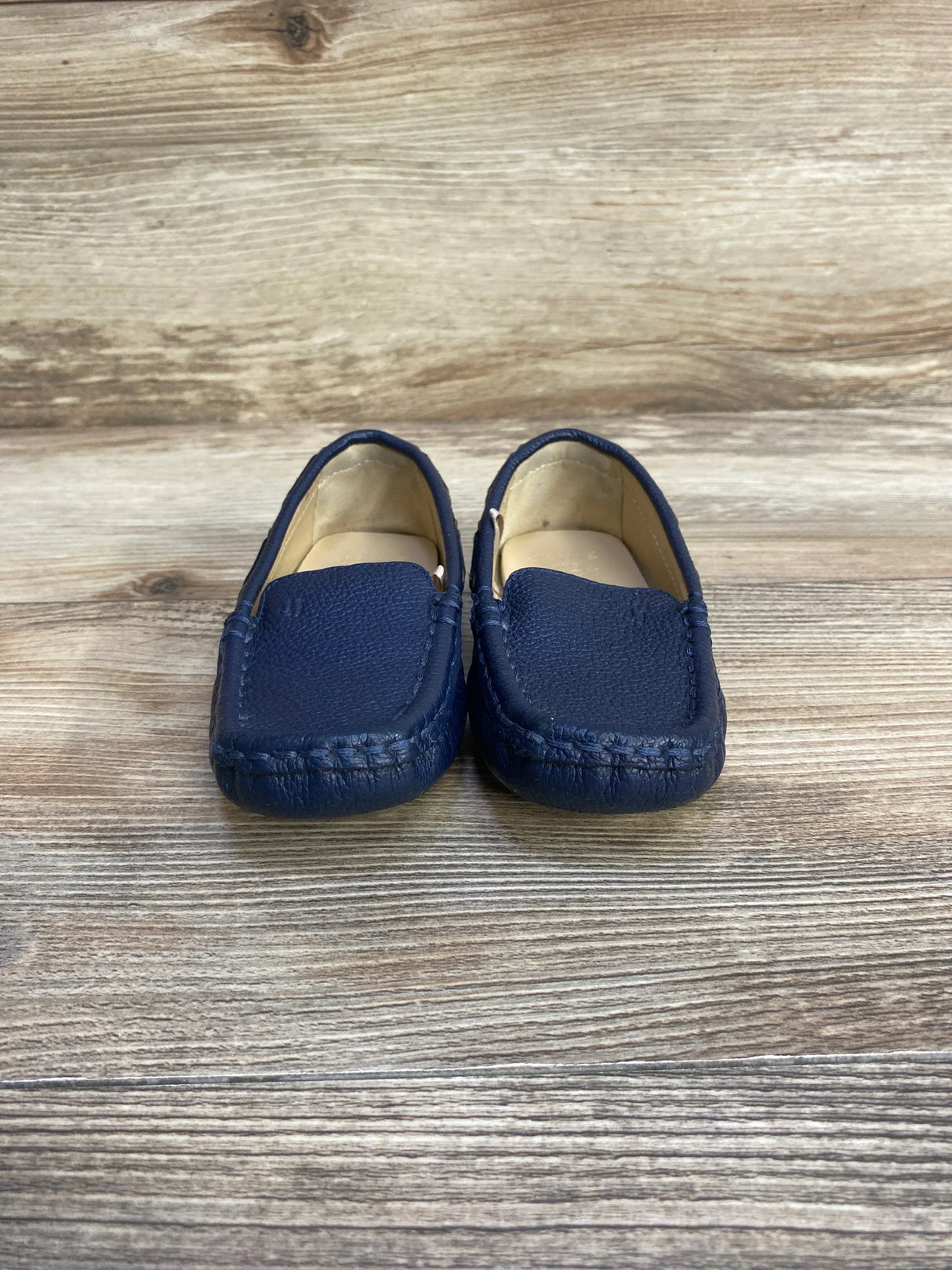 Front view of Janie and Jack navy leather driving shoes, toddler size 8C, showing stitched moc toe on wood-look background