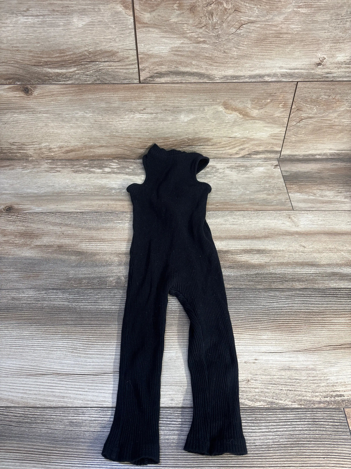 Front view of black Shein ribbed jumpsuit showcasing its sleeveless design on a wood-look floor