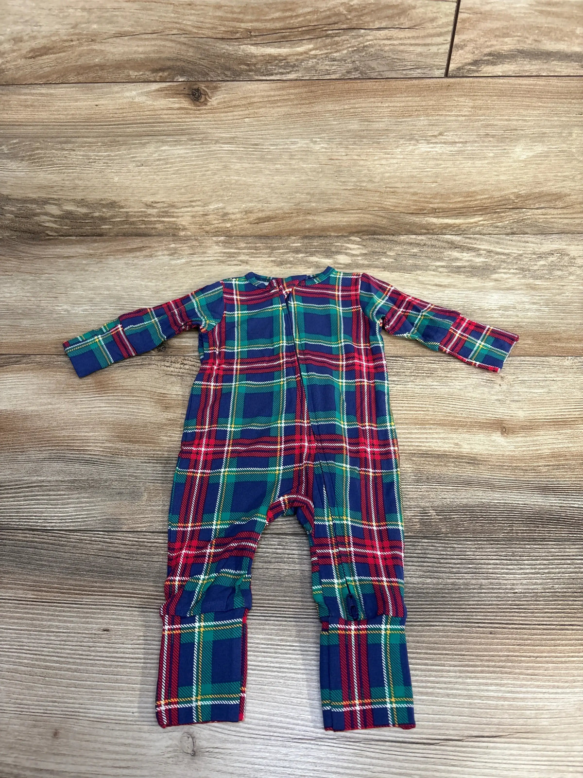 baby onesie with red, green, and blue plaid pattern laid flat on wooden surface