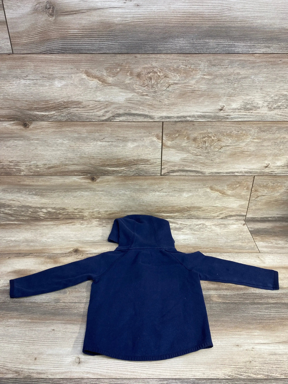 Navy blue toddler hooded sweatshirt laid flat on wooden floor background