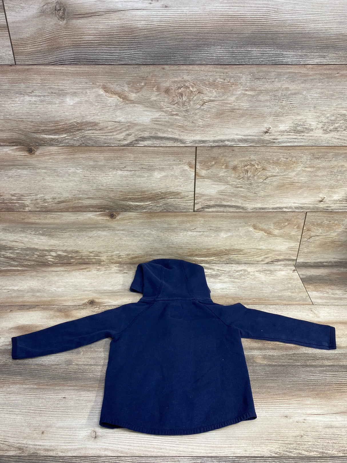 Navy blue toddler hooded sweatshirt laid flat on wooden floor background