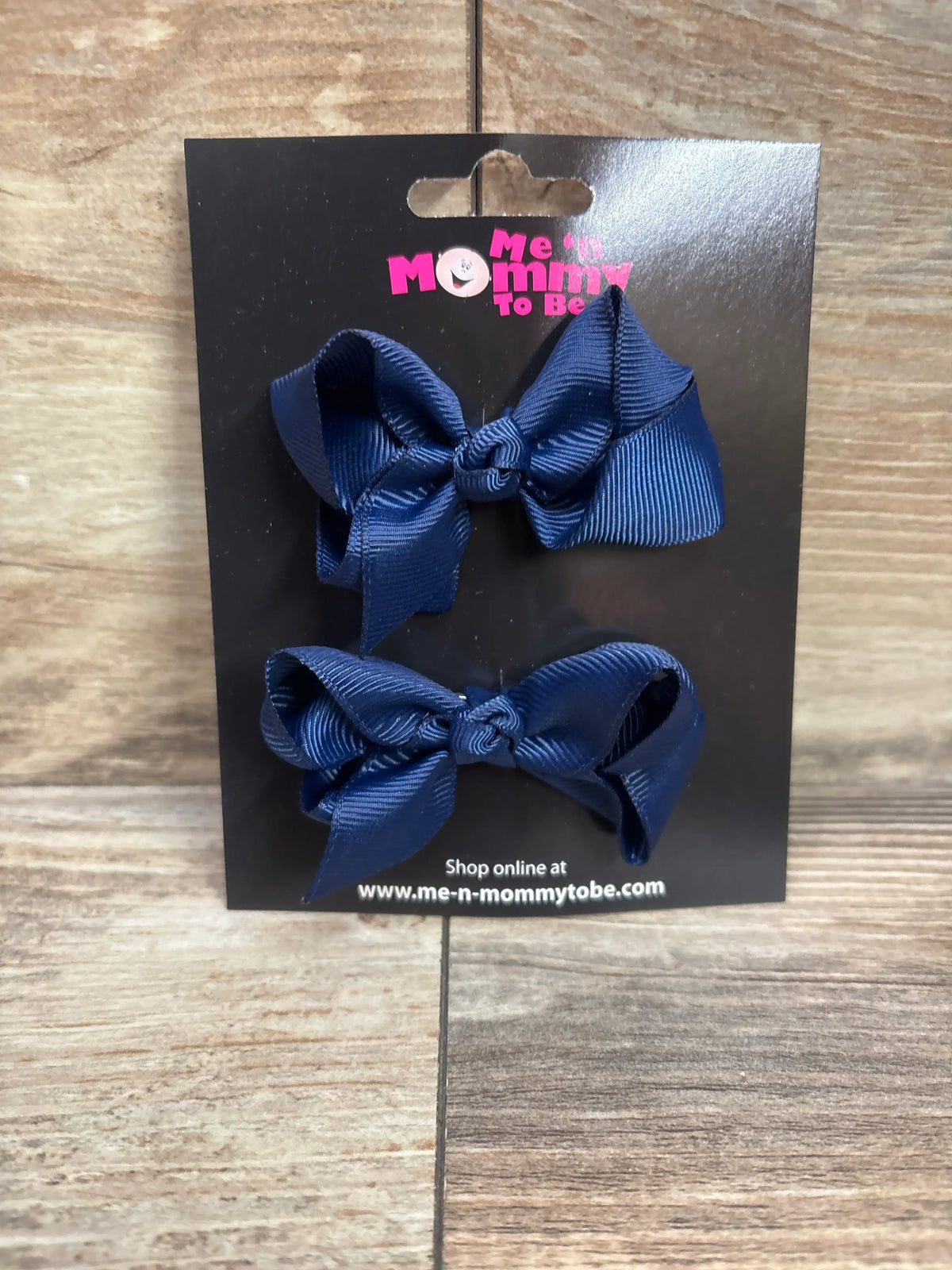 Two navy blue grosgrain hair bows on a Me n Mommy To Be branded display card.