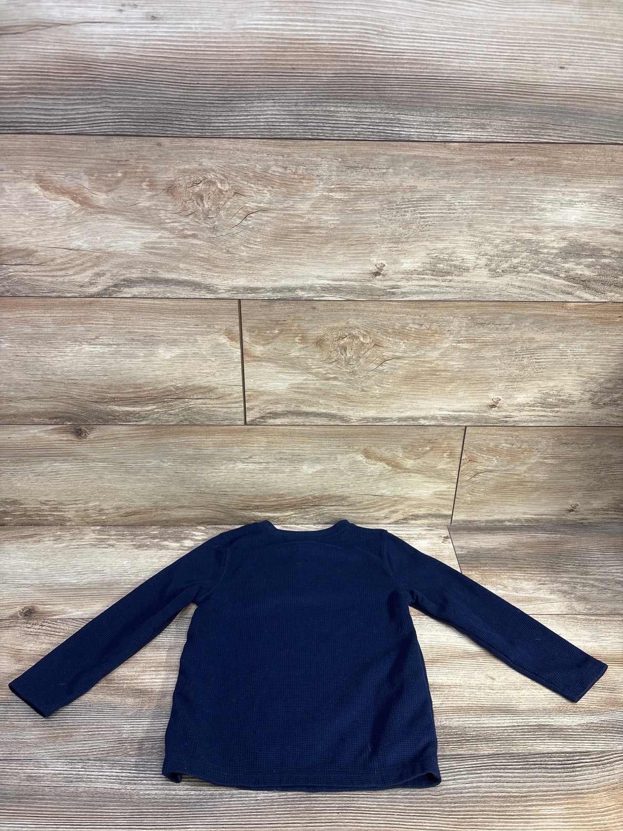Back view of navy waffle-knit toddler henley size 3T showing long sleeves and texture on wood background