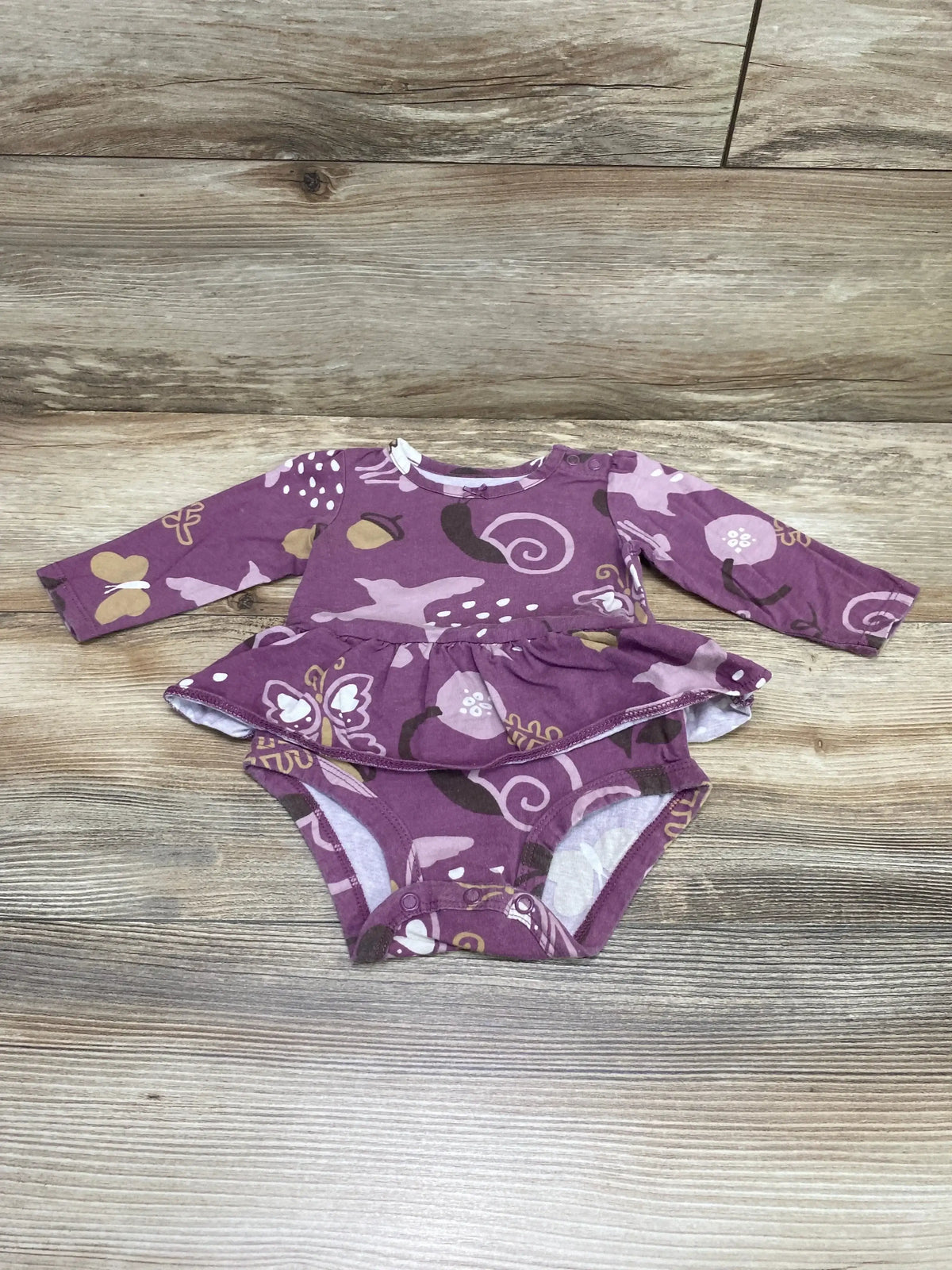 Flat-lay of Carter’s purple long-sleeve skirted bodysuit 6M showing butterfly print and crotch snaps on wood floor