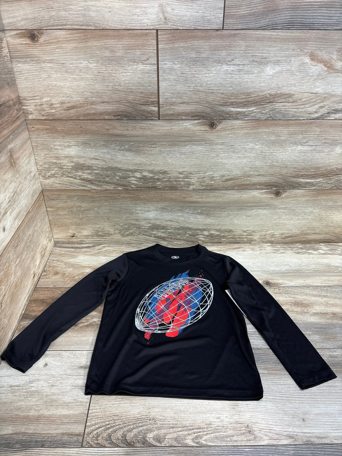 Black long sleeve kids shirt with red and blue abstract globe graphic on wood floor