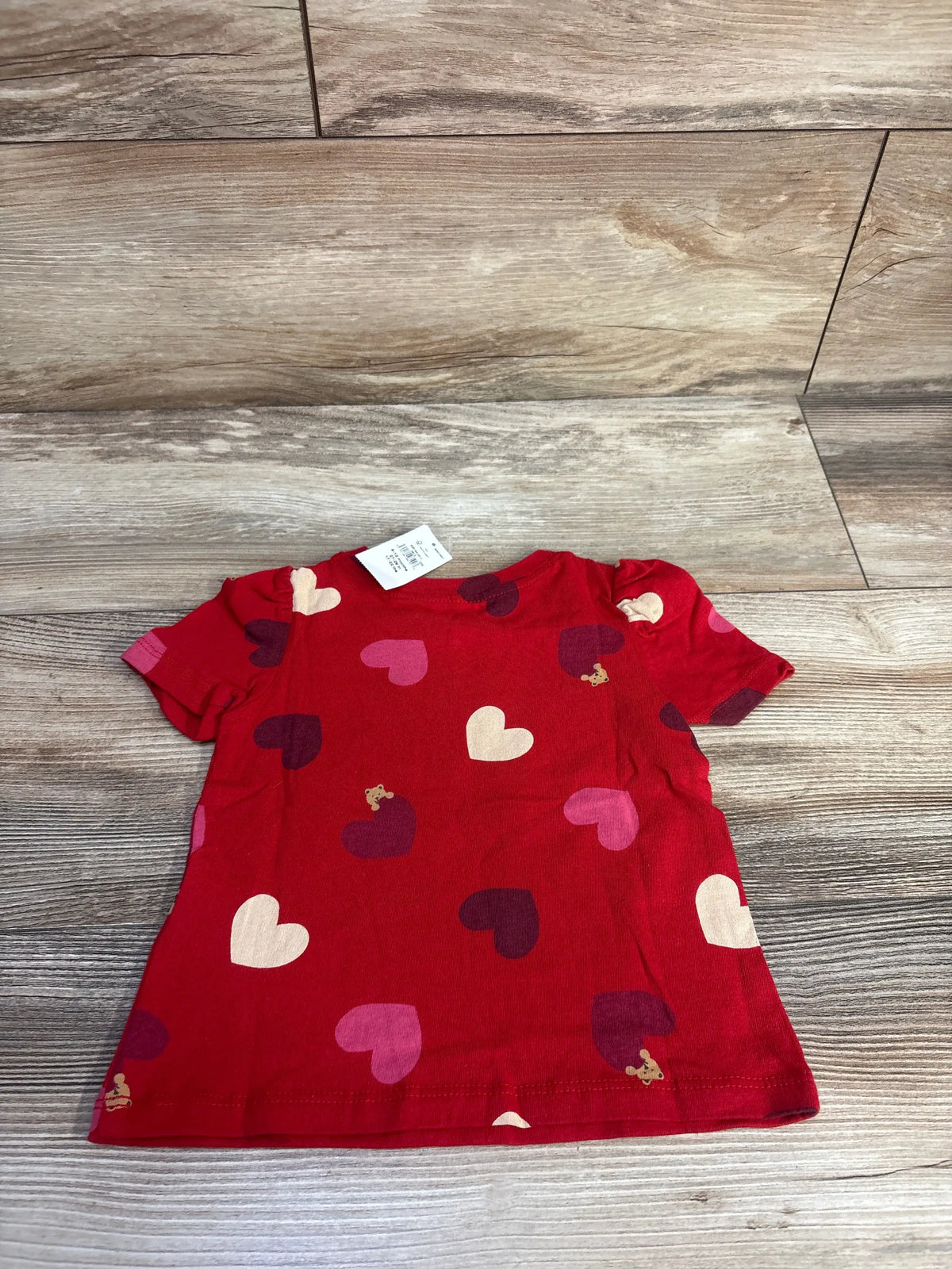 Front view of Baby Gap red puff sleeve pocket shirt showcasing heart pattern and puff sleeves on a wood-look floor